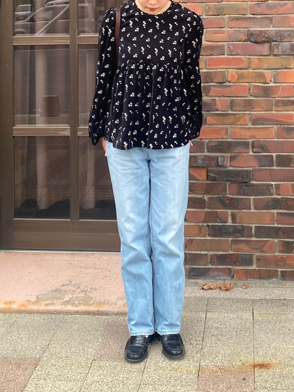 ブラック系のTシャツ/カットソー、ブラウン系のメッセンジャーバッグ、ブルー系のデニムパンツを着用したレディースの秋コーディネートの2枚目の写真