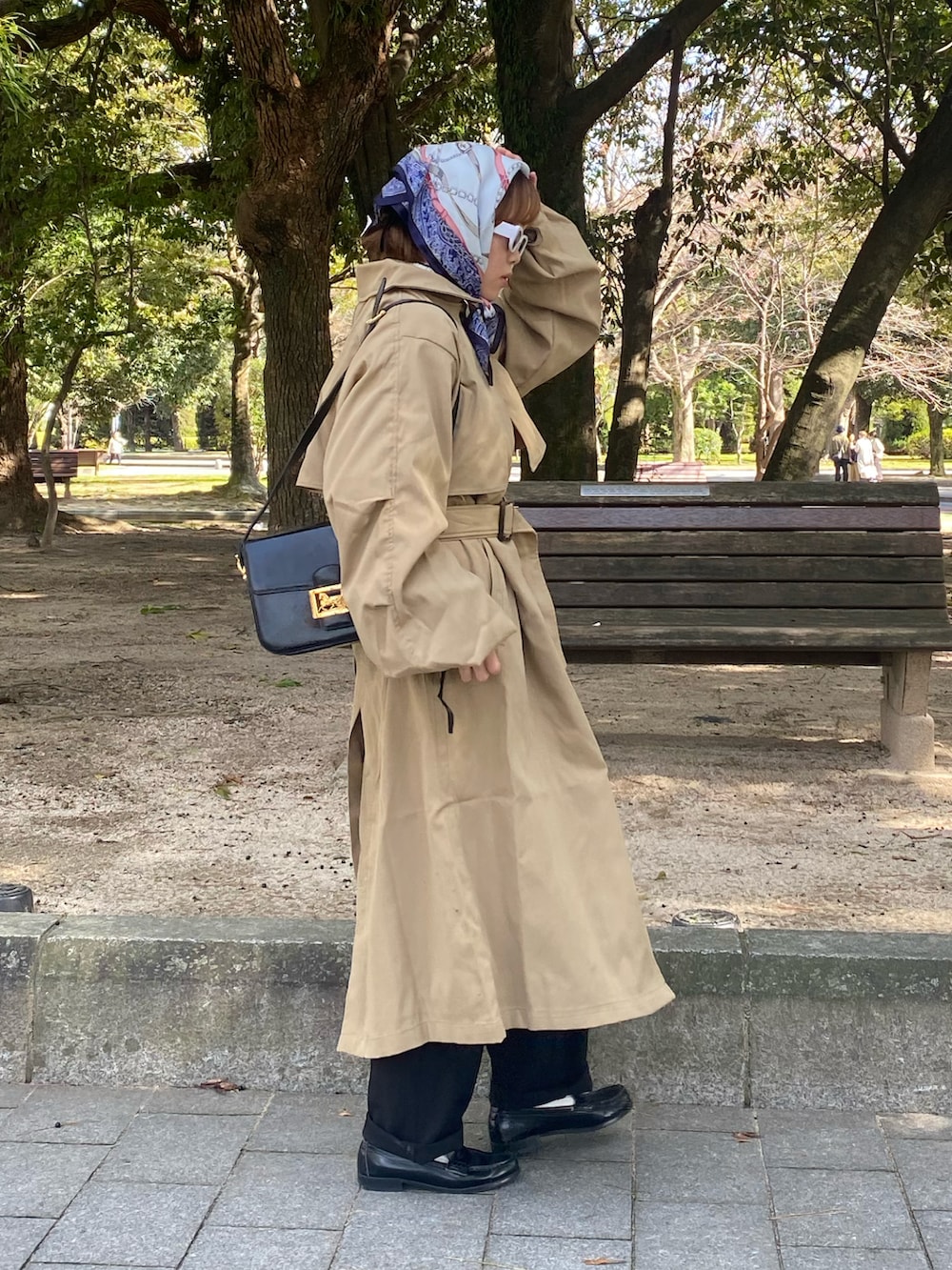 ベージュ系のステンカラーコート、ブラック系のローファーを着用したレディースの冬コーディネートの2枚目の写真