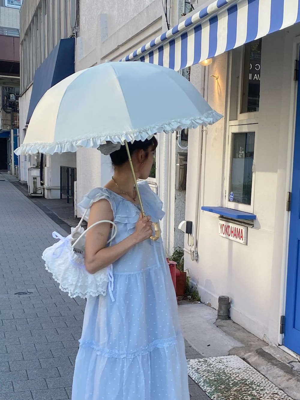 ブラック系のサンダル、ブルー系のワンピース、ホワイト系のハンドバッグを着用したレディースの夏コーディネートの2枚目の写真