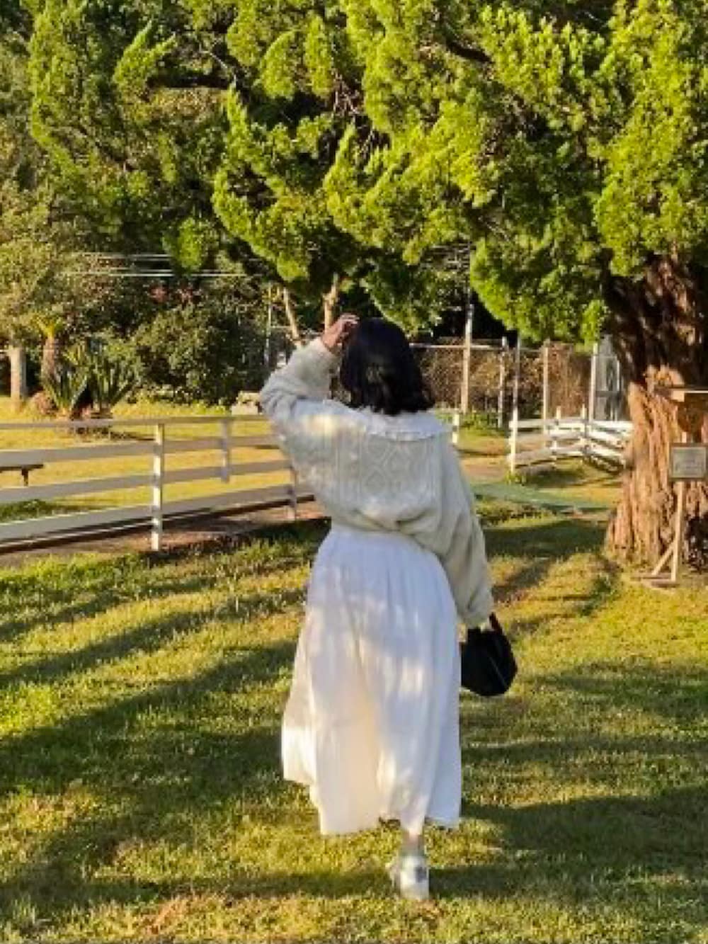 ホワイト系のスカート、ブラック系のハンドバッグ、ホワイト系のニット/セーターを着用したレディースの秋コーディネートの3枚目の写真