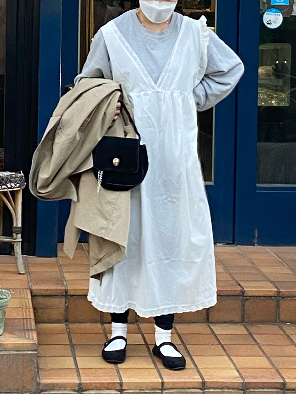 ホワイト系のワンピース、ブラック系のバレエシューズ、ベージュ系のトレンチコートを着用したレディースの春コーディネートの3枚目の写真