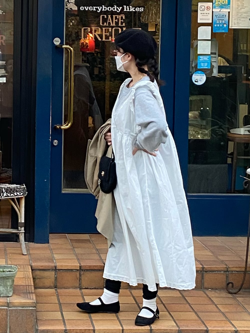 ホワイト系のワンピース、ブラック系のバレエシューズ、ベージュ系のトレンチコートを着用したレディースの春コーディネートの2枚目の写真