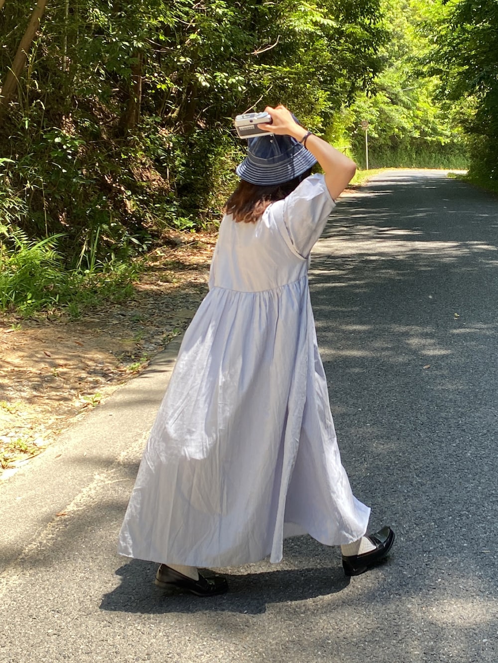 ブルー系のシャツワンピース、ブラック系のローファー、ブルー系のハットを着用したレディースの夏コーディネートの3枚目の写真