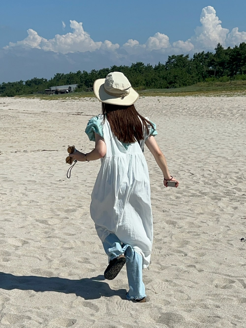 グリーン系のシャツ/ブラウス、ホワイト系のワンピース、ブルー系のデニムパンツを着用したレディースの秋コーディネートの2枚目の写真