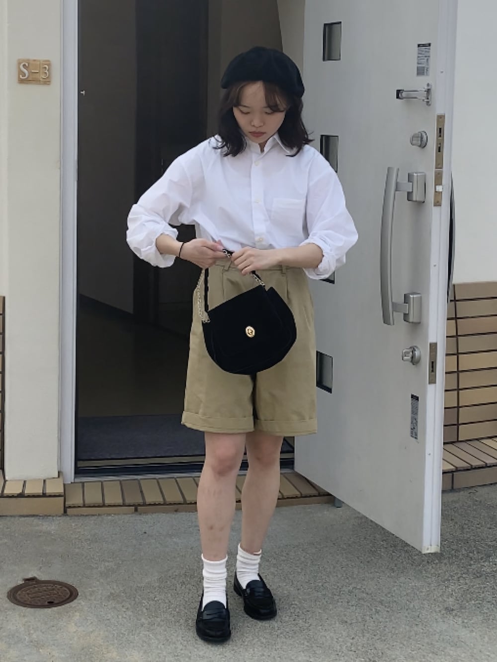 ブラック系のローファー、ベージュ系のチノパンツ、ブラック系のショルダーバッグを着用したレディースの春コーディネートの2枚目の写真