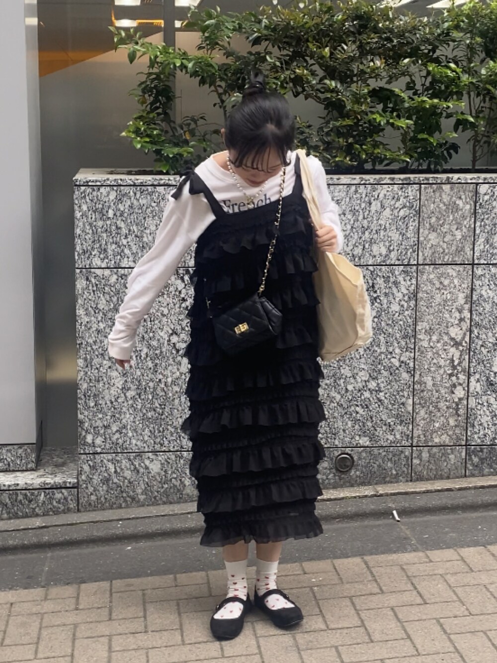 ブラック系のショルダーバッグ、ブラック系のワンピース、ホワイト系のTシャツ/カットソーを着用したレディースの春コーディネートの2枚目の写真