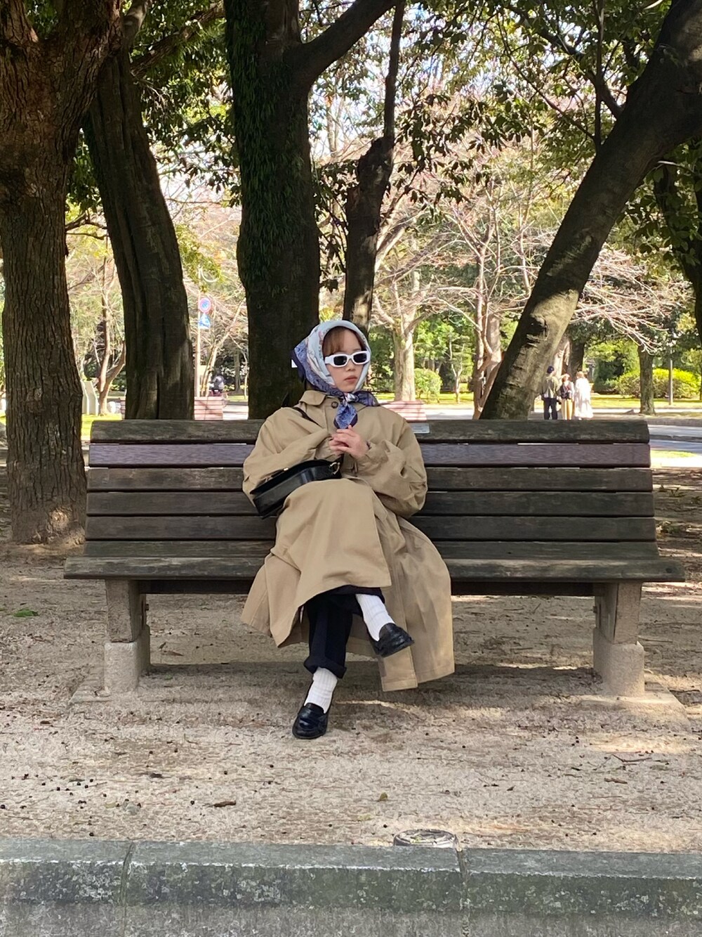 ベージュ系のステンカラーコート、ブラック系のローファーを着用したレディースの冬コーディネートの3枚目の写真