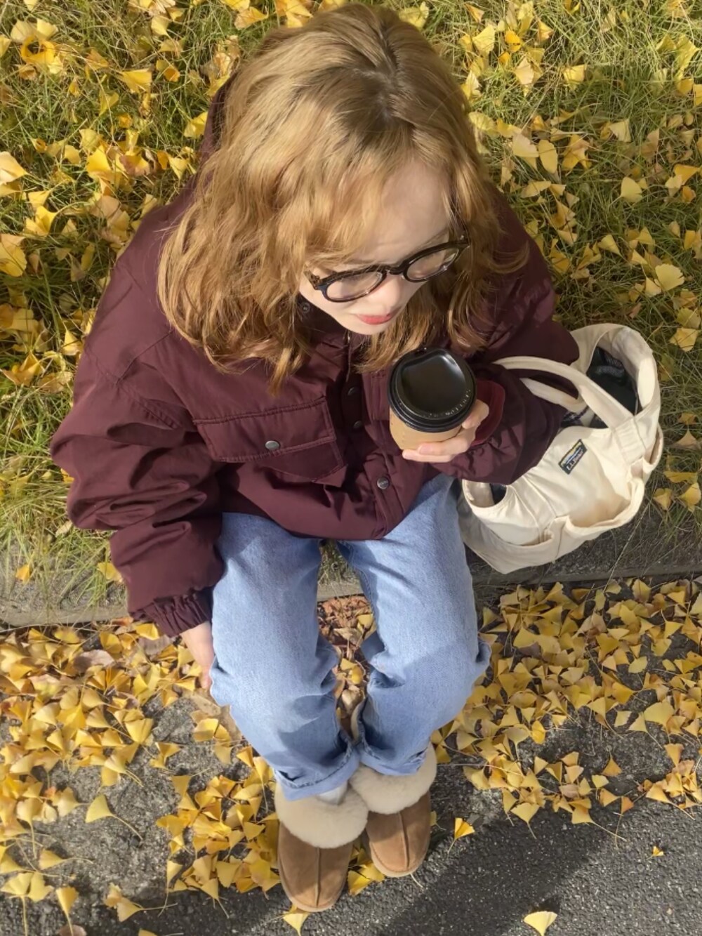 ブルー系のデニムパンツ、ブラウン系のスリッポン、ホワイト系のトートバッグを着用したレディースの秋コーディネートの2枚目の写真