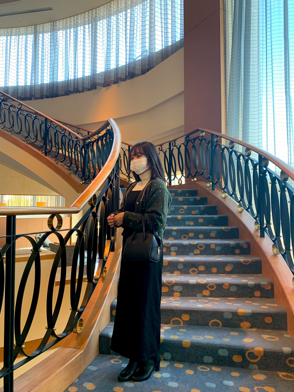 グリーン系のカーディガン/ボレロ、ブラック系のブーツ、ブラック系のオールインワン・サロペットを着用したレディースの冬コーディネートの2枚目の写真