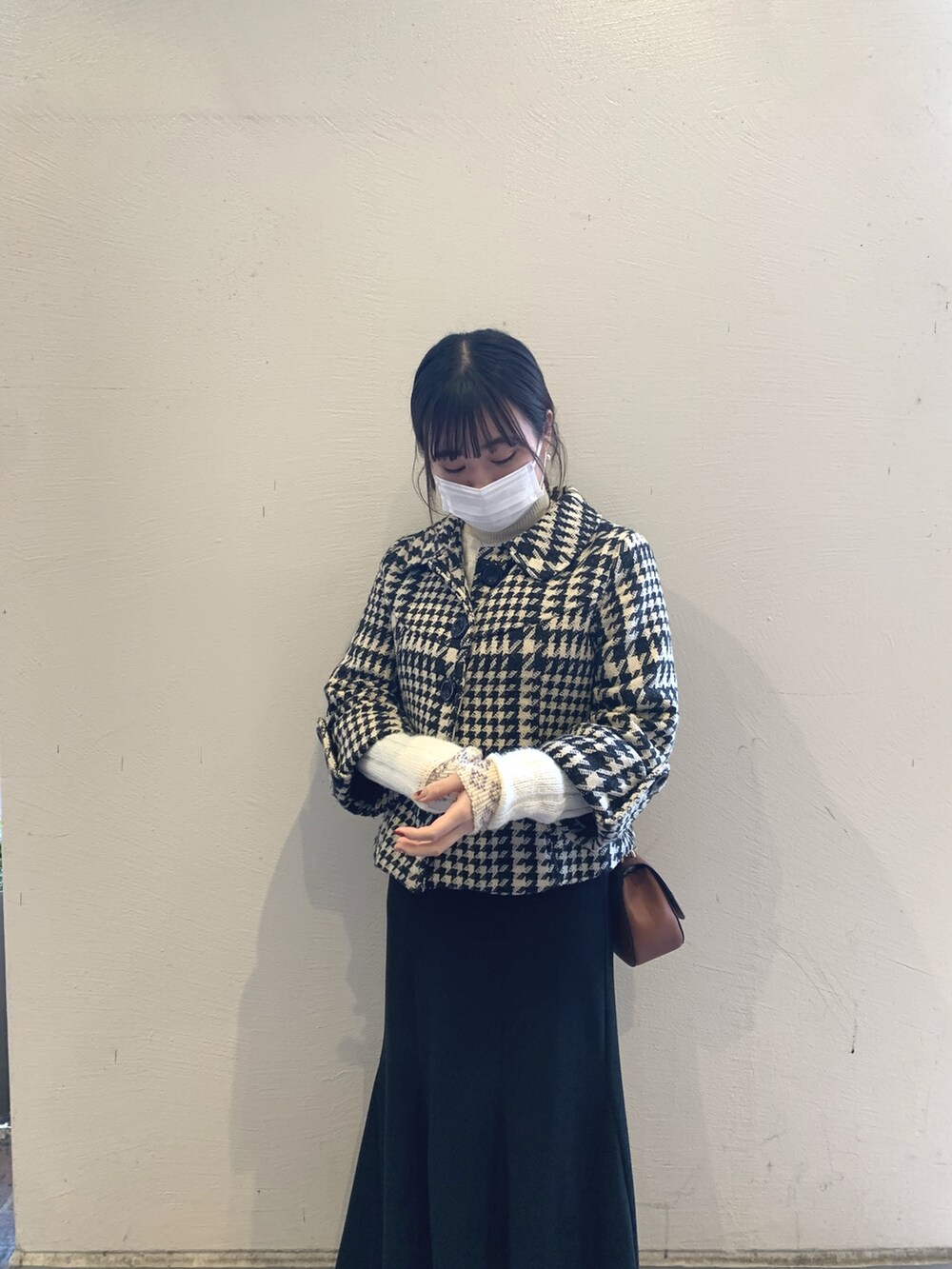 ブラック系のスカート、ブラック系のブーツ、ホワイト系のニット/セーターを着用したレディースの冬コーディネートの2枚目の写真