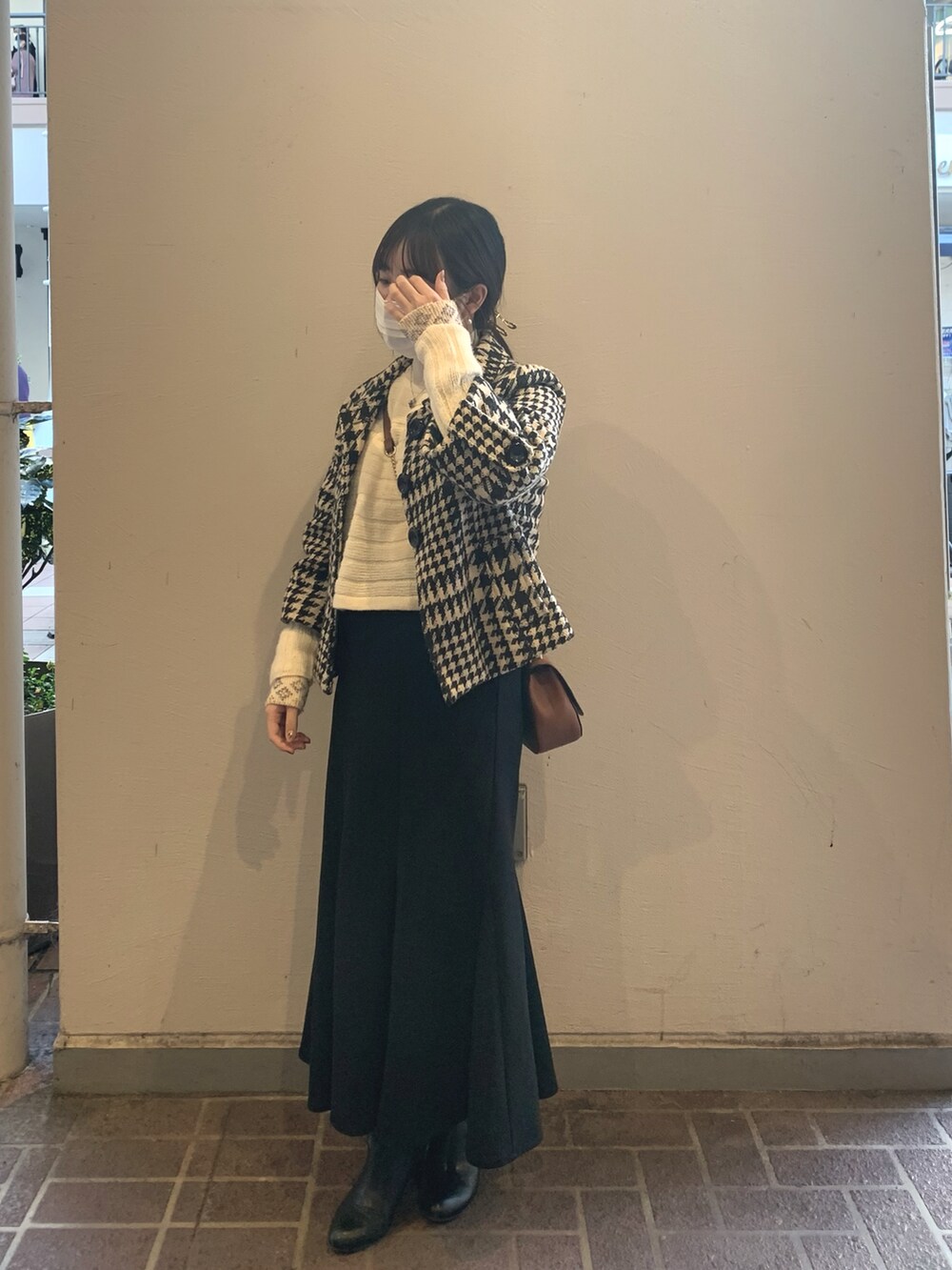 ブラック系のスカート、ブラック系のブーツ、ホワイト系のニット/セーターを着用したレディースの冬コーディネートの3枚目の写真