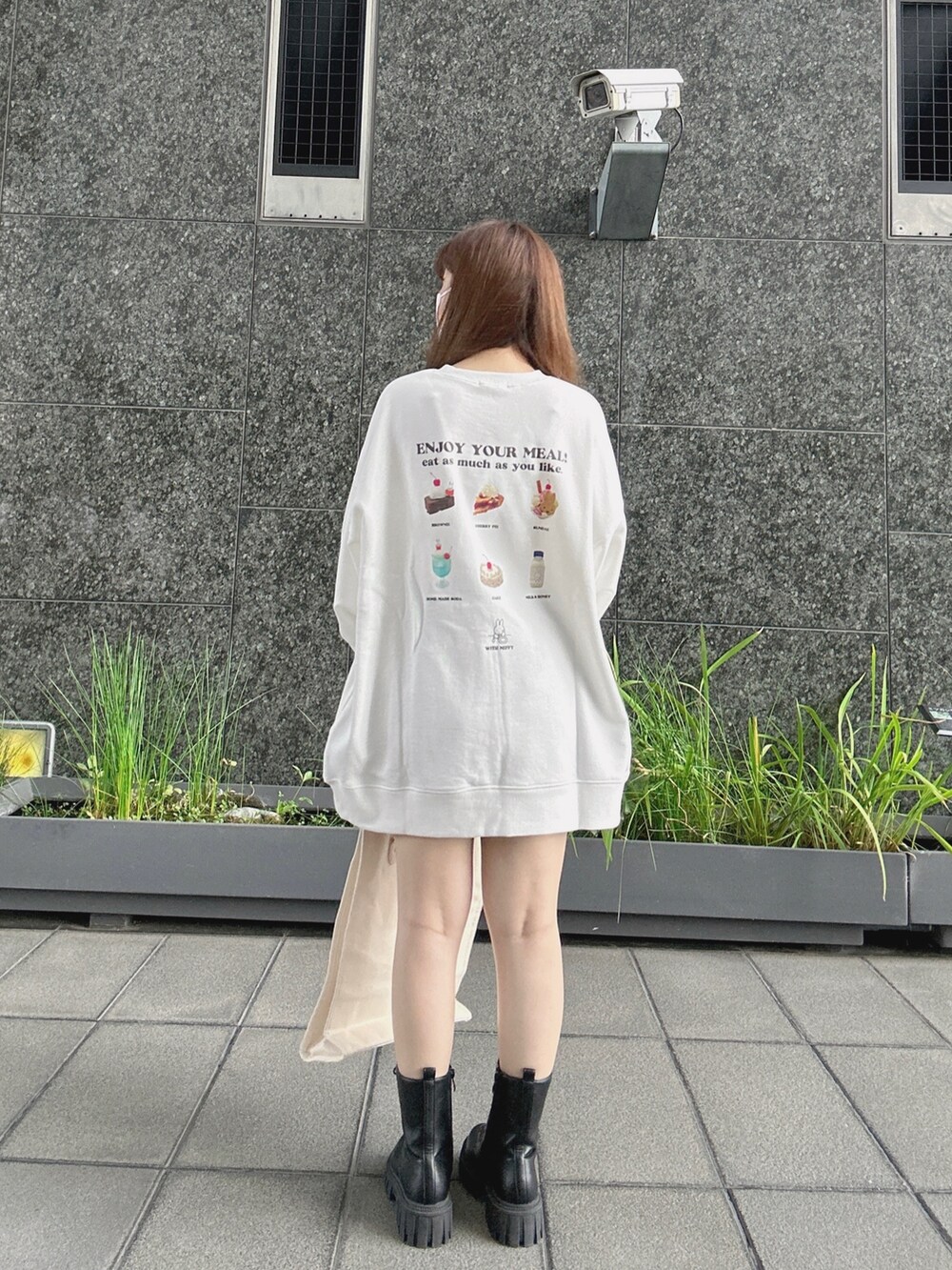 ホワイト系のスウェット、ブラウン系のトートバッグ、ブラック系のブーツを着用したレディースの秋コーディネートの2枚目の写真