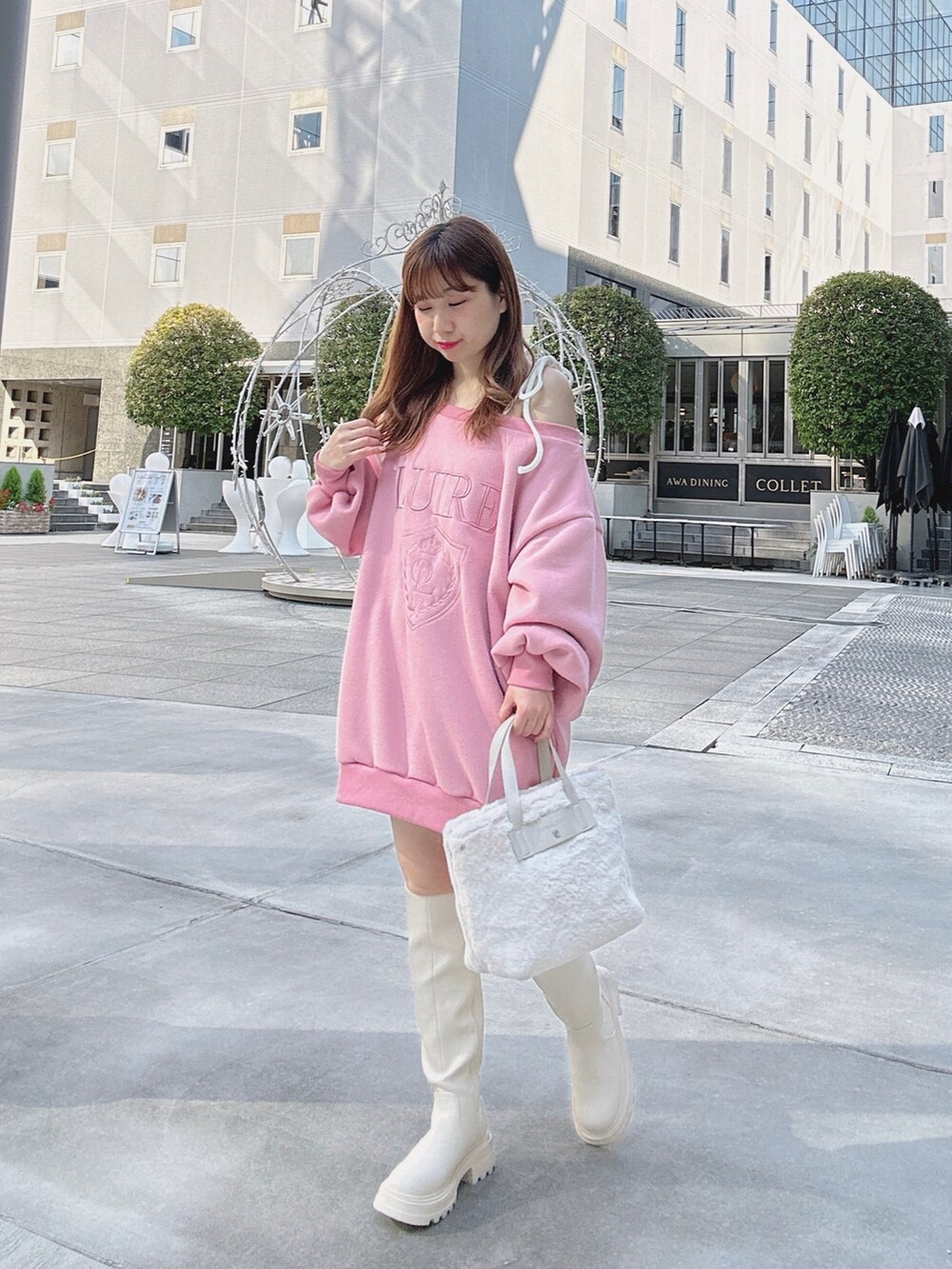ピンク系のスウェット、ホワイト系のブーツ、ホワイト系のショルダーバッグを着用したレディースの秋コーディネートの2枚目の写真
