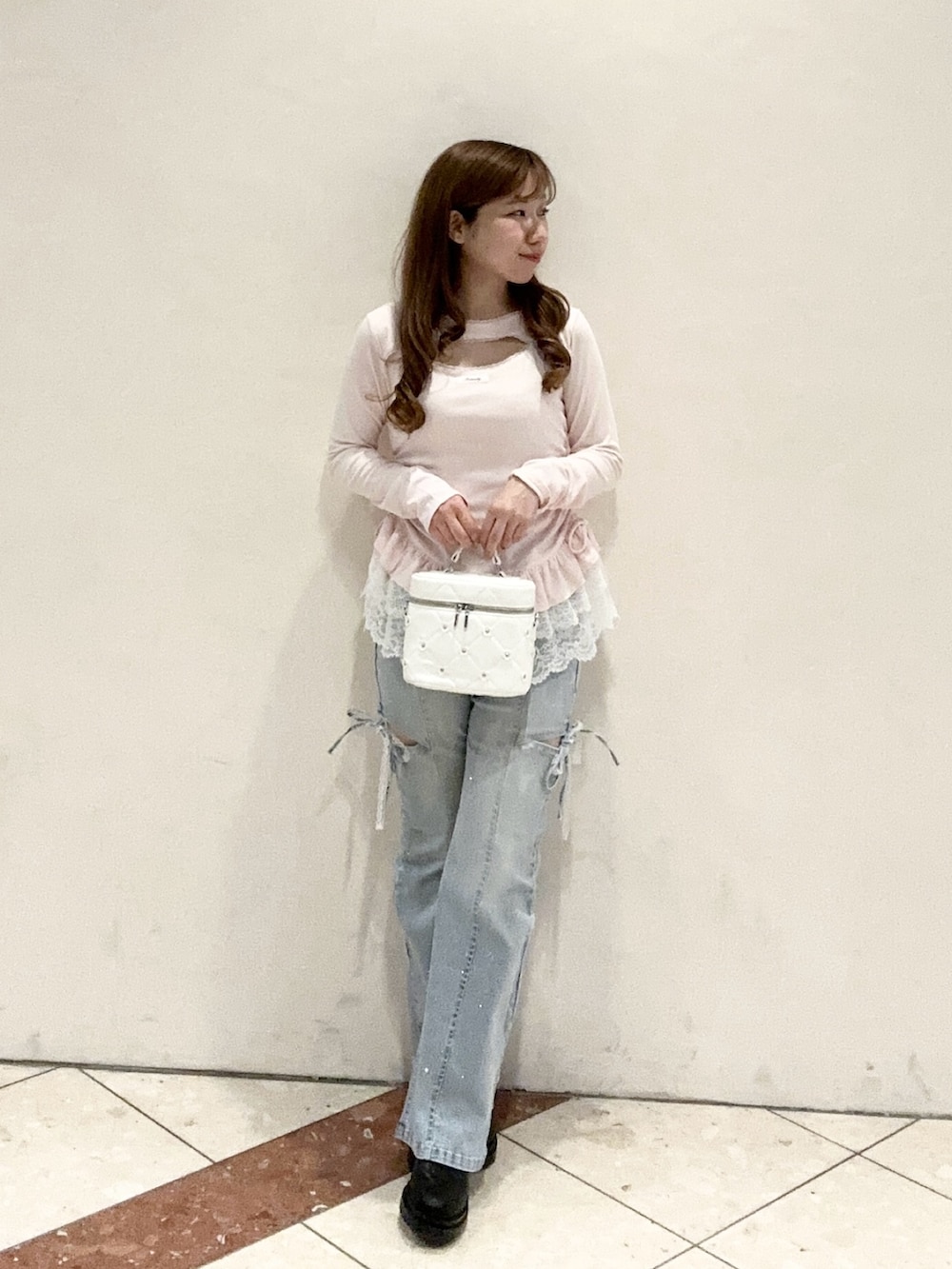 ホワイト系のハンドバッグ、ピンク系のTシャツ/カットソー、ブルー系のデニムパンツを着用したレディースの冬コーディネートの2枚目の写真