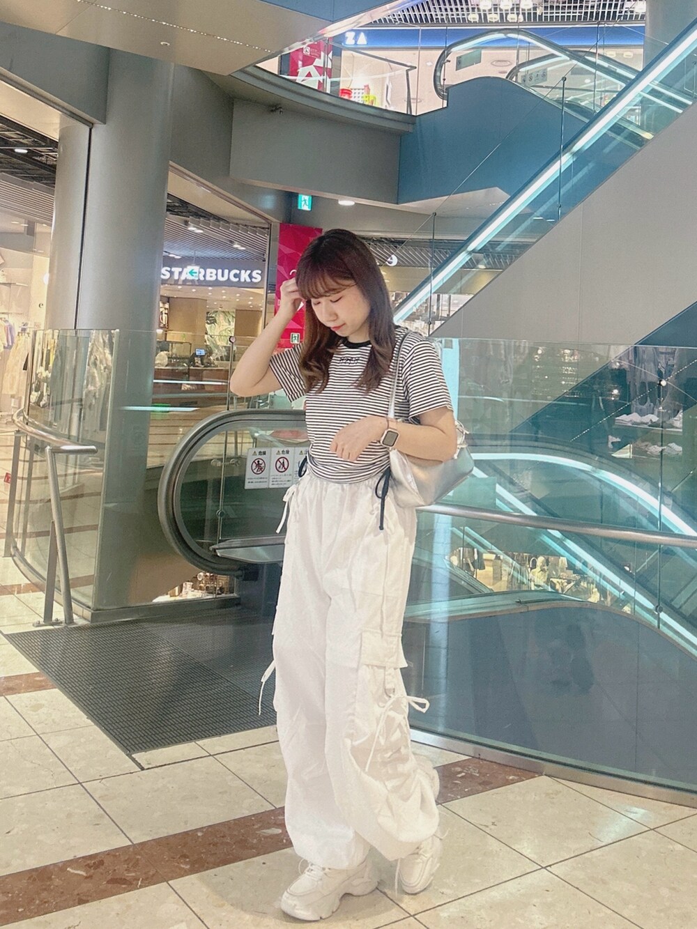 ブラック系のTシャツ/カットソー、ホワイト系のカーゴパンツ、シルバー系のショルダーバッグを着用したレディースの夏コーディネートの3枚目の写真