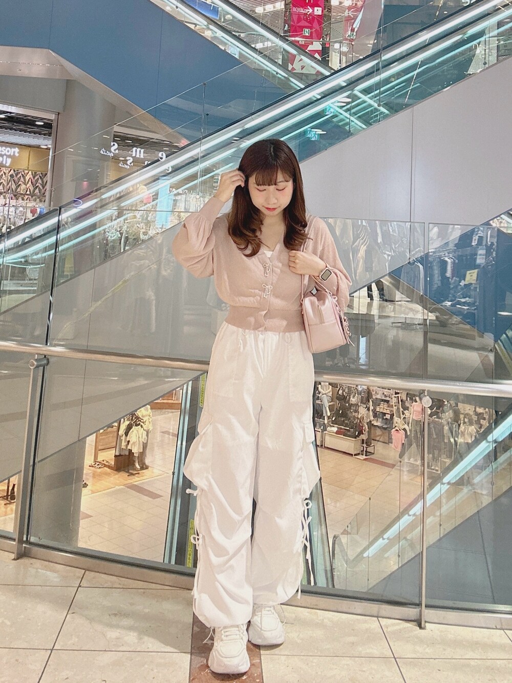 ピンク系のカーディガン/ボレロ、ピンク系のショルダーバッグ、ホワイト系のカーゴパンツを着用したレディースの夏コーディネートの2枚目の写真