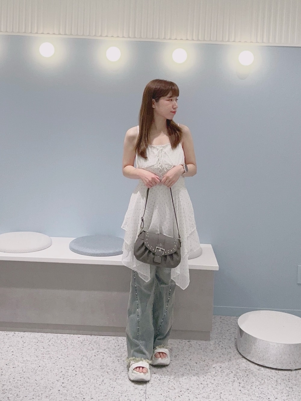 ブルー系のデニムパンツ、ホワイト系のワンピース、ホワイト系のサンダルを着用したレディースの夏コーディネートの3枚目の写真