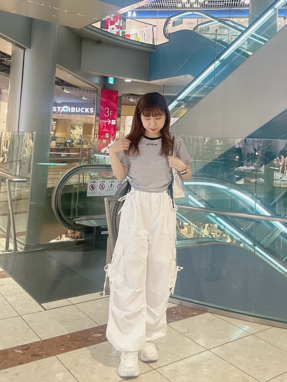 ブラック系のTシャツ/カットソー、ホワイト系のカーゴパンツ、シルバー系のショルダーバッグを着用したレディースの夏コーディネートの2枚目の写真