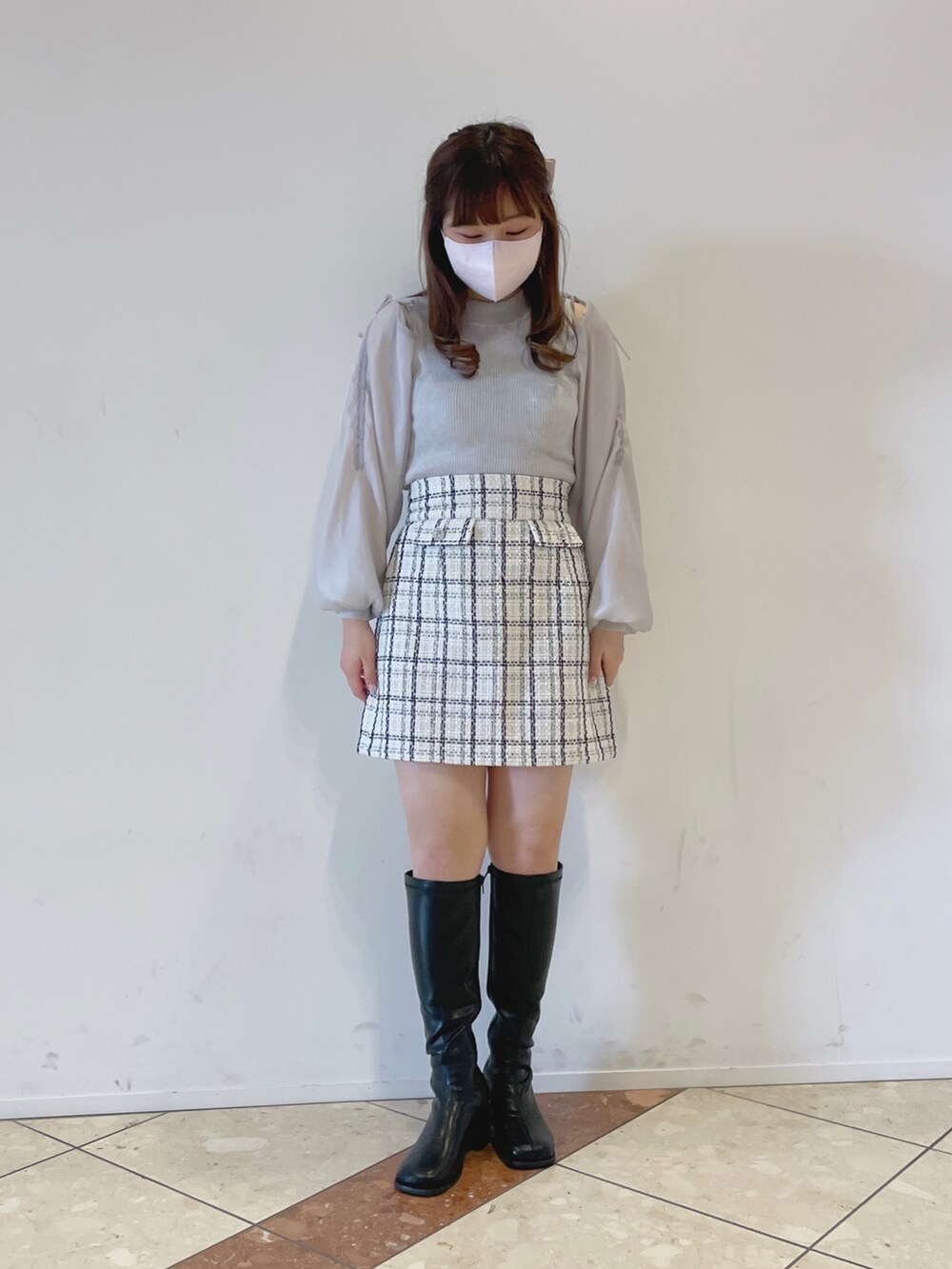 グレー系のニット/セーター、ホワイト系のスカート、ブラック系のその他シューズを着用したレディースの冬コーディネートの2枚目の写真