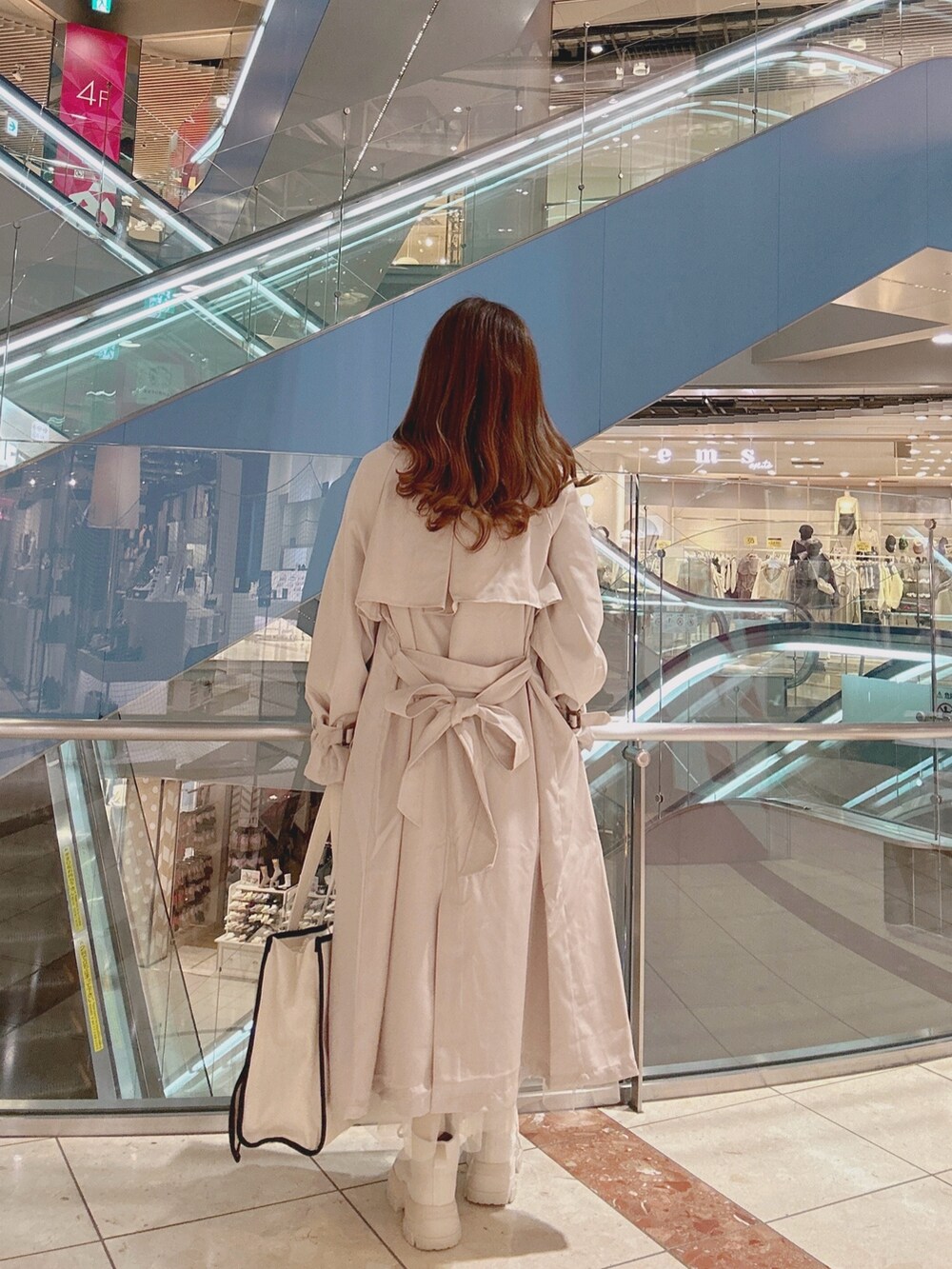 ベージュ系のトレンチコート、ホワイト系のスニーカー、ホワイト系のトートバッグを着用したレディースの冬コーディネートの3枚目の写真