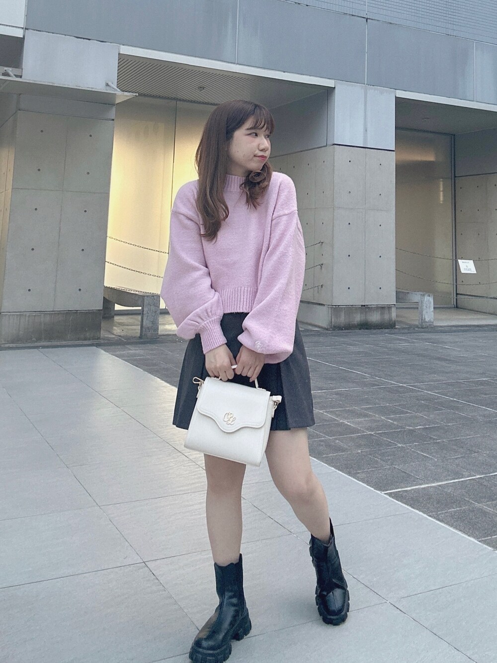 グレー系のスカート、ピンク系のニット/セーター、ホワイト系のショルダーバッグを着用したレディースの秋コーディネートの2枚目の写真