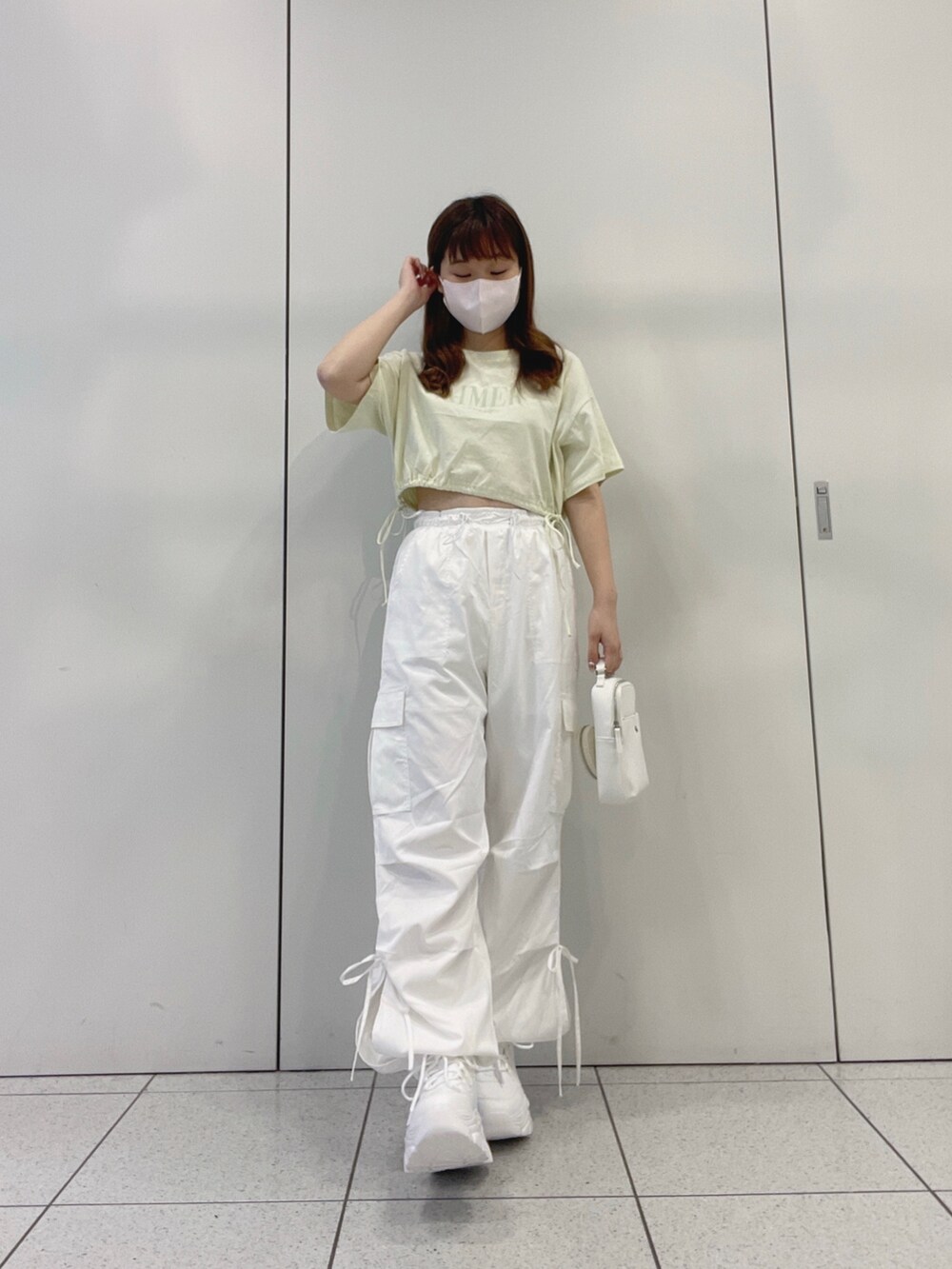 グリーン系のTシャツ/カットソー、ホワイト系のスニーカー、ホワイト系のカーゴパンツを着用したレディースの夏コーディネートの2枚目の写真