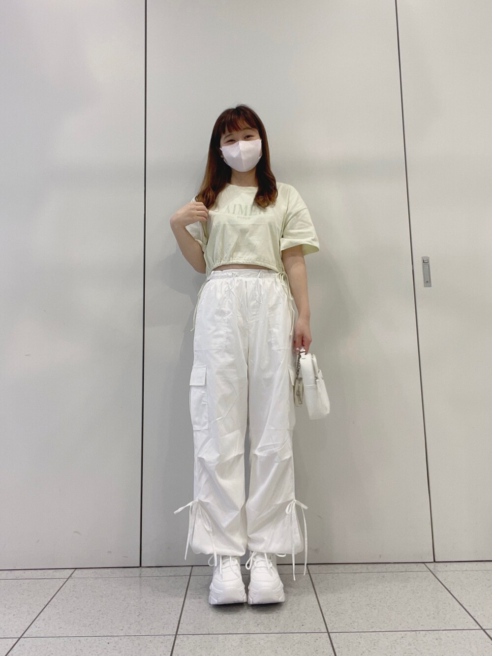 グリーン系のTシャツ/カットソー、ホワイト系のスニーカー、ホワイト系のカーゴパンツを着用したレディースの夏コーディネートの3枚目の写真