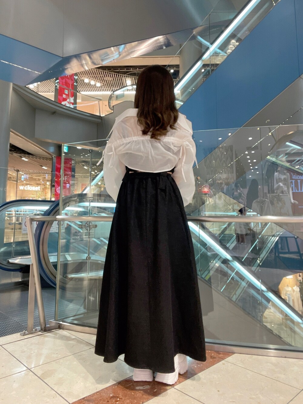 ブラック系のジャンパースカート、ホワイト系のシャツ/ブラウス、ホワイト系のスニーカーを着用したレディースの夏コーディネートの4枚目の写真