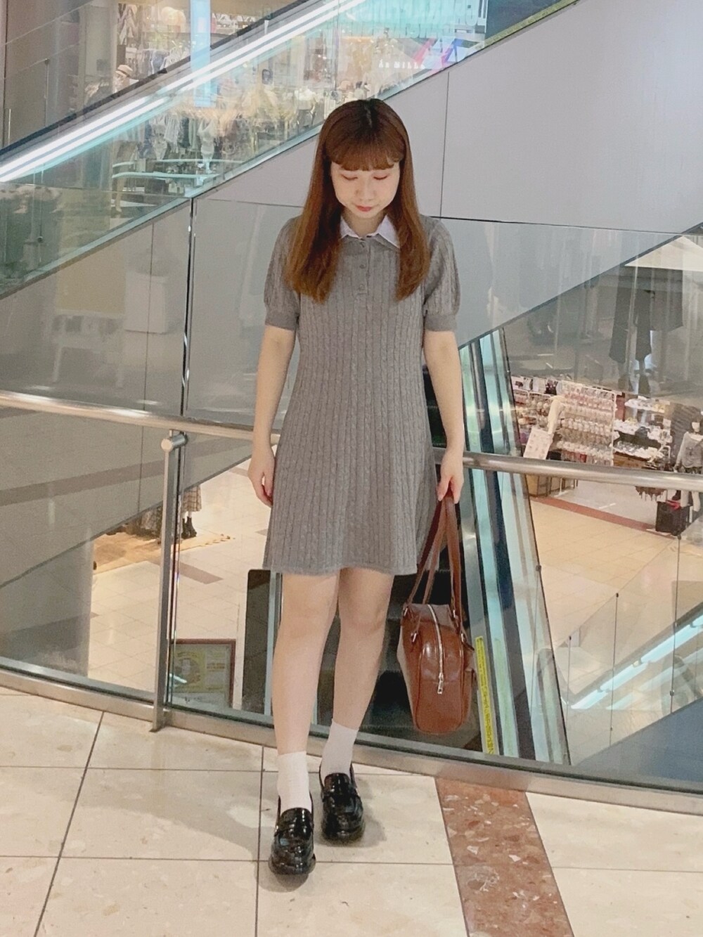 グレー系のワンピース、ブラウン系のボストンバッグ、ブラック系のローファーを着用したレディースの夏コーディネートの2枚目の写真