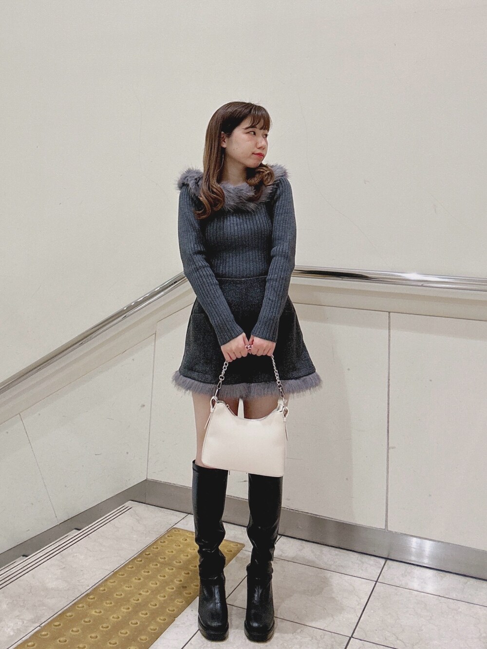 グレー系のニット/セーター、グレー系のその他パンツ、ホワイト系のショルダーバッグを着用したレディースの冬コーディネートの2枚目の写真
