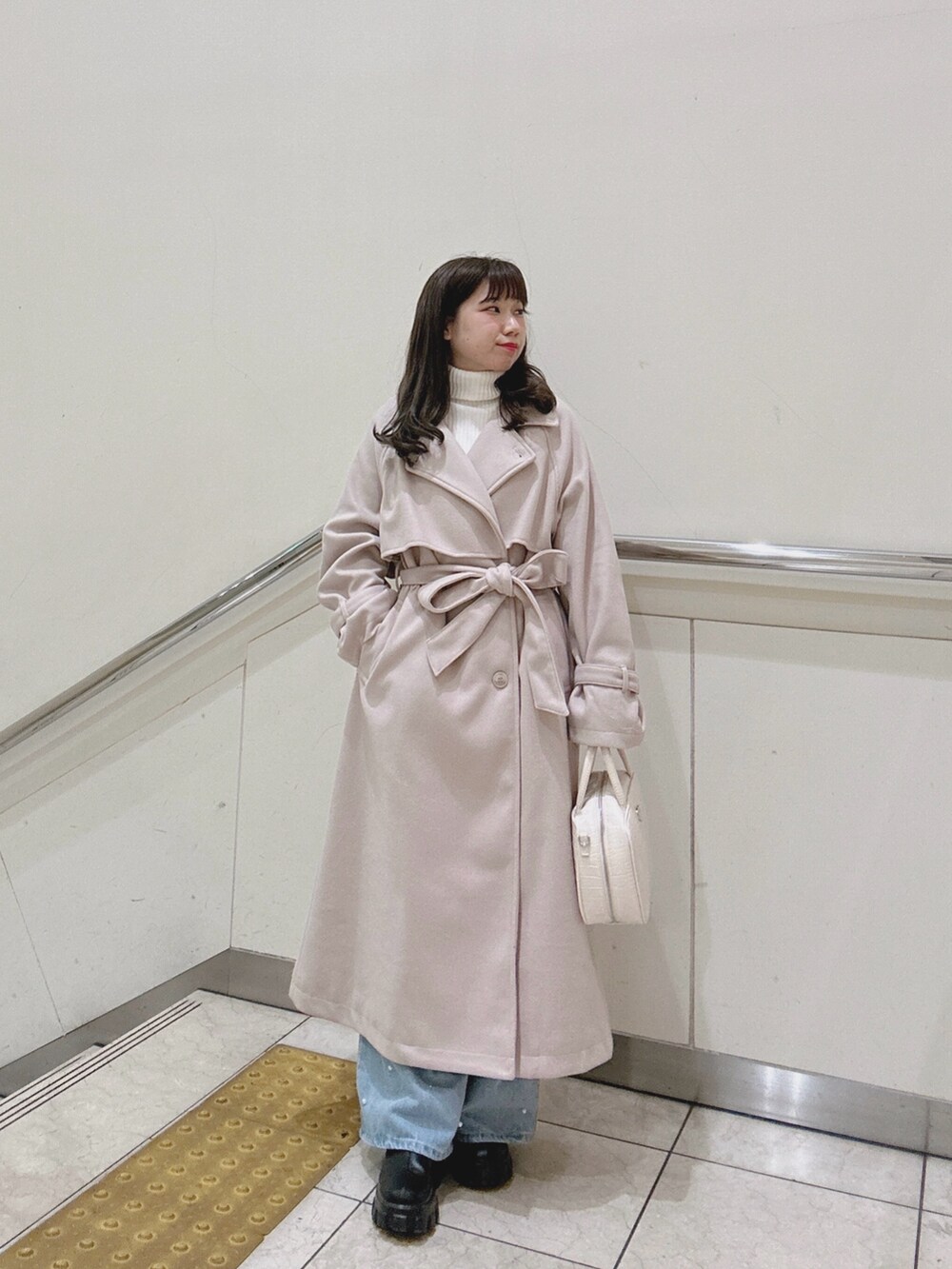 ホワイト系のショルダーバッグ、ホワイト系のニット/セーター、ホワイト系のステンカラーコートを着用したレディースの冬コーディネートの3枚目の写真