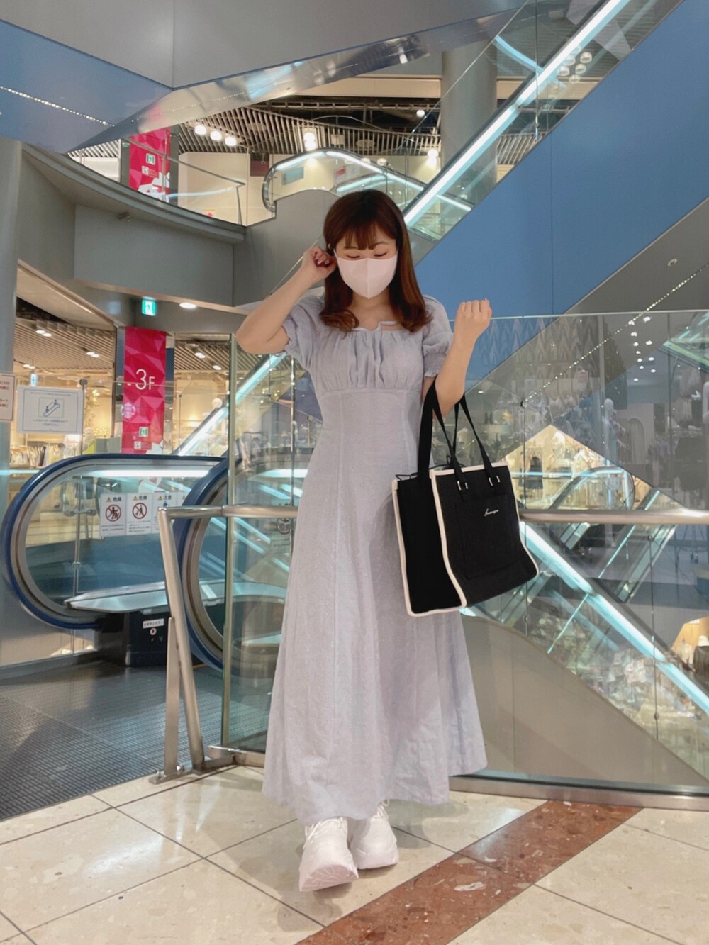 ブルー系のワンピース/ドレス、ブラック系のトートバッグ、ホワイト系のスニーカーを着用したレディースの春コーディネートの2枚目の写真