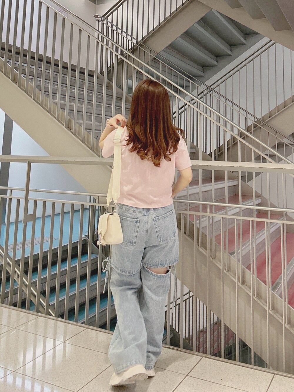 ブルー系のデニムパンツ、ピンク系のTシャツ/カットソー、ホワイト系のショルダーバッグを着用したレディースの夏コーディネートの3枚目の写真