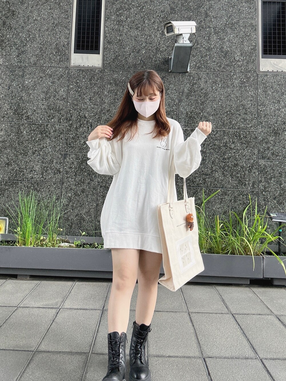 ホワイト系のスウェット、ブラウン系のトートバッグ、ブラック系のブーツを着用したレディースの秋コーディネートの3枚目の写真