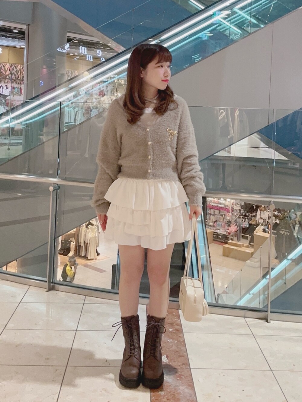 ブラウン系のカーディガン/ボレロ、ホワイト系のスカート、ホワイト系のショルダーバッグを着用したレディースの秋コーディネートの2枚目の写真