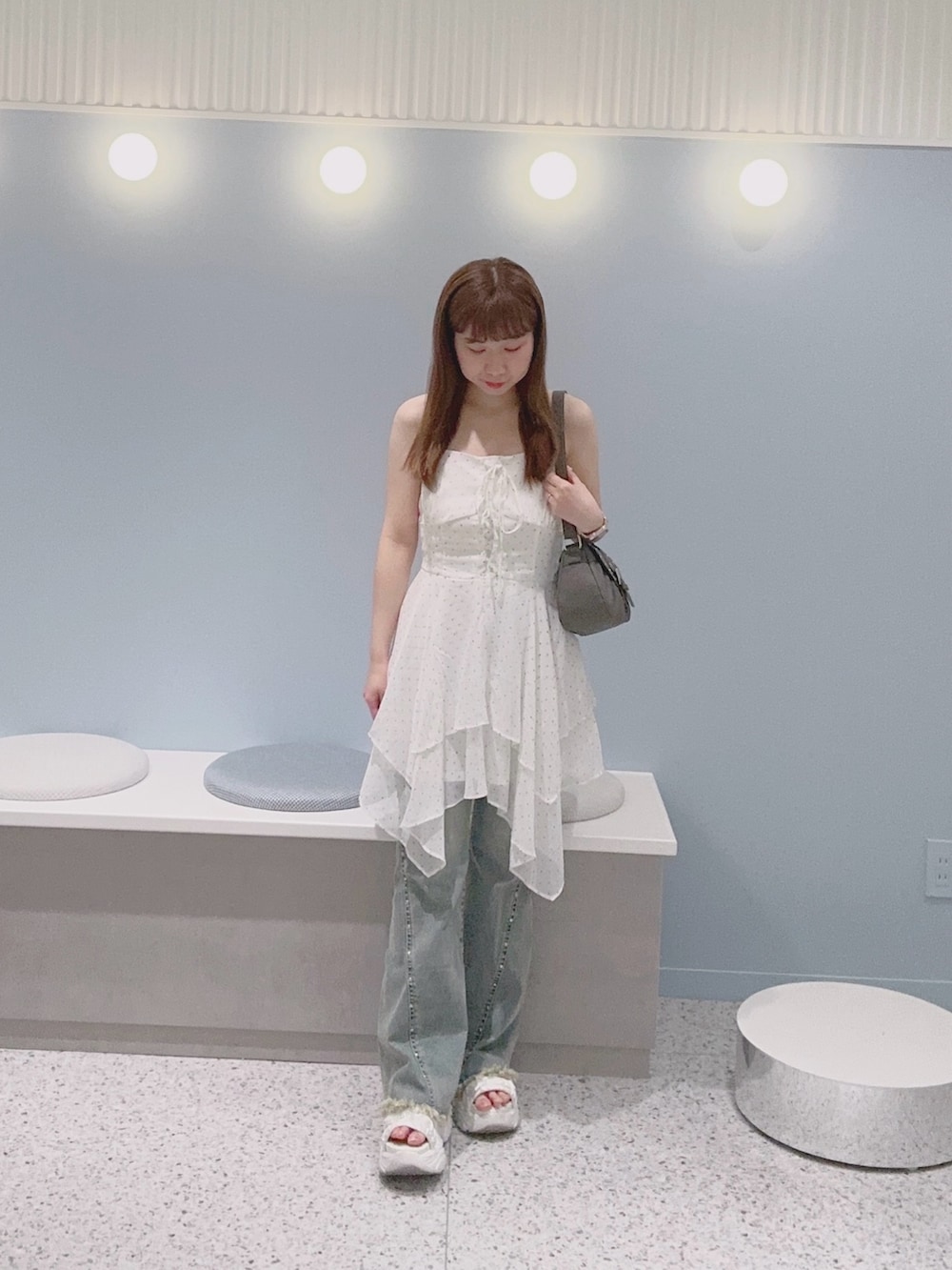 ブルー系のデニムパンツ、ホワイト系のワンピース、ホワイト系のサンダルを着用したレディースの夏コーディネートの2枚目の写真