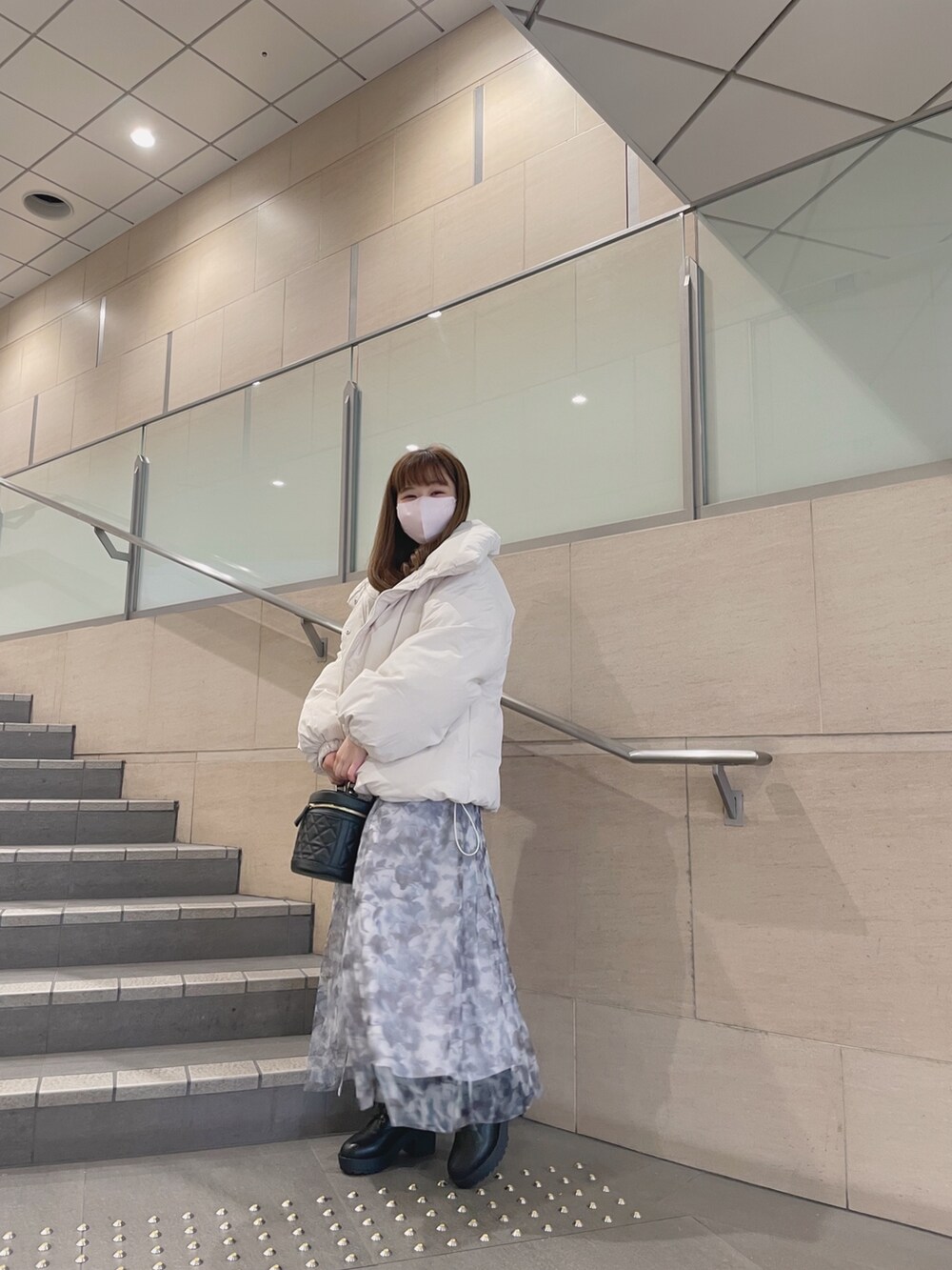 ホワイト系のダウンジャケット/コート、ブラック系のショルダーバッグ、グレー系のワンピースを着用したレディースの冬コーディネートの2枚目の写真