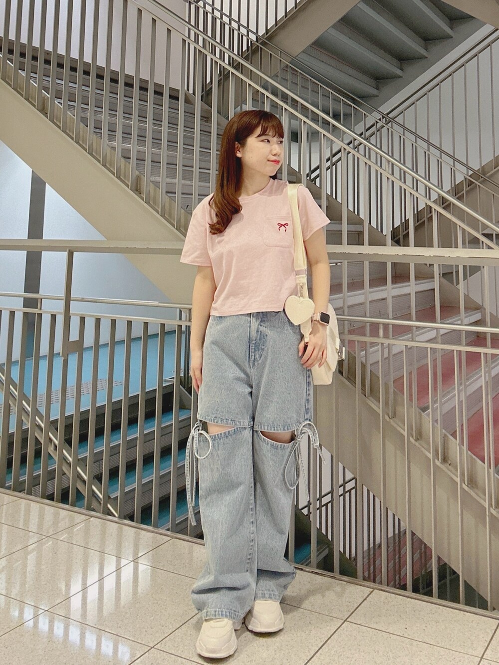 ブルー系のデニムパンツ、ピンク系のTシャツ/カットソー、ホワイト系のショルダーバッグを着用したレディースの夏コーディネートの2枚目の写真