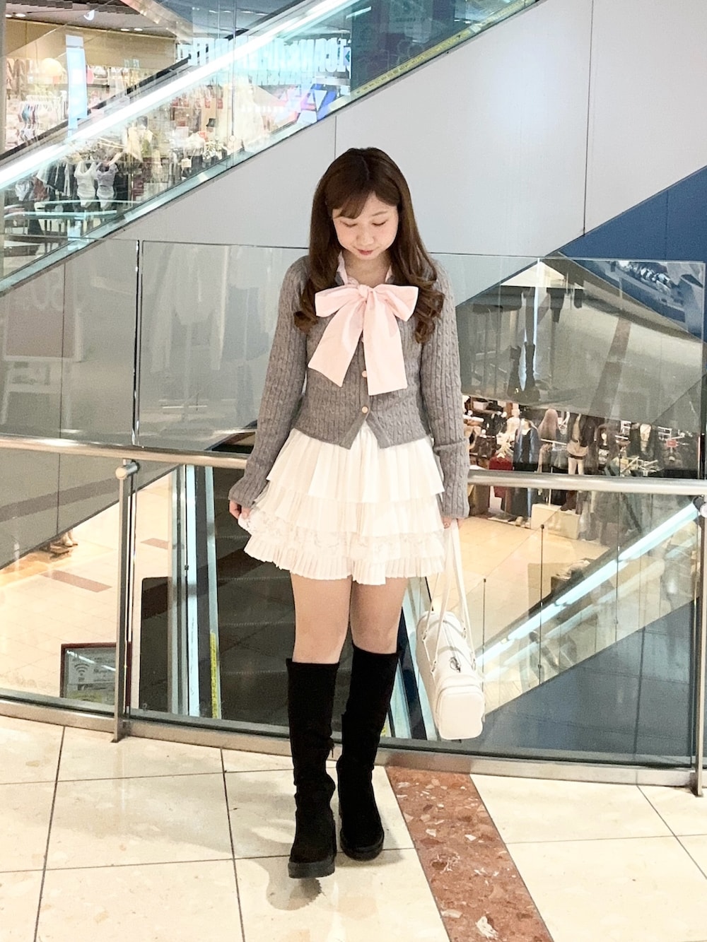 グレー系のニット/セーター、ホワイト系のスカート、ホワイト系のトートバッグを着用したレディースの冬コーディネートの2枚目の写真