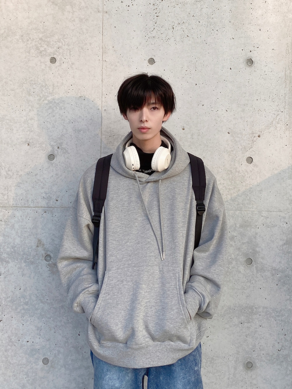 グレー系のパーカー、ブラック系のバックパック/リュック、ブルー系のスラックスを着用したメンズの春コーディネートの2枚目の写真