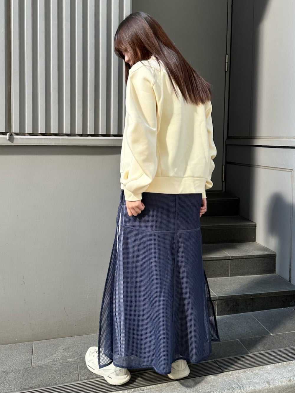 ブルー系のスカート、イエロー系のトップスを着用したレディースの春コーディネートの3枚目の写真