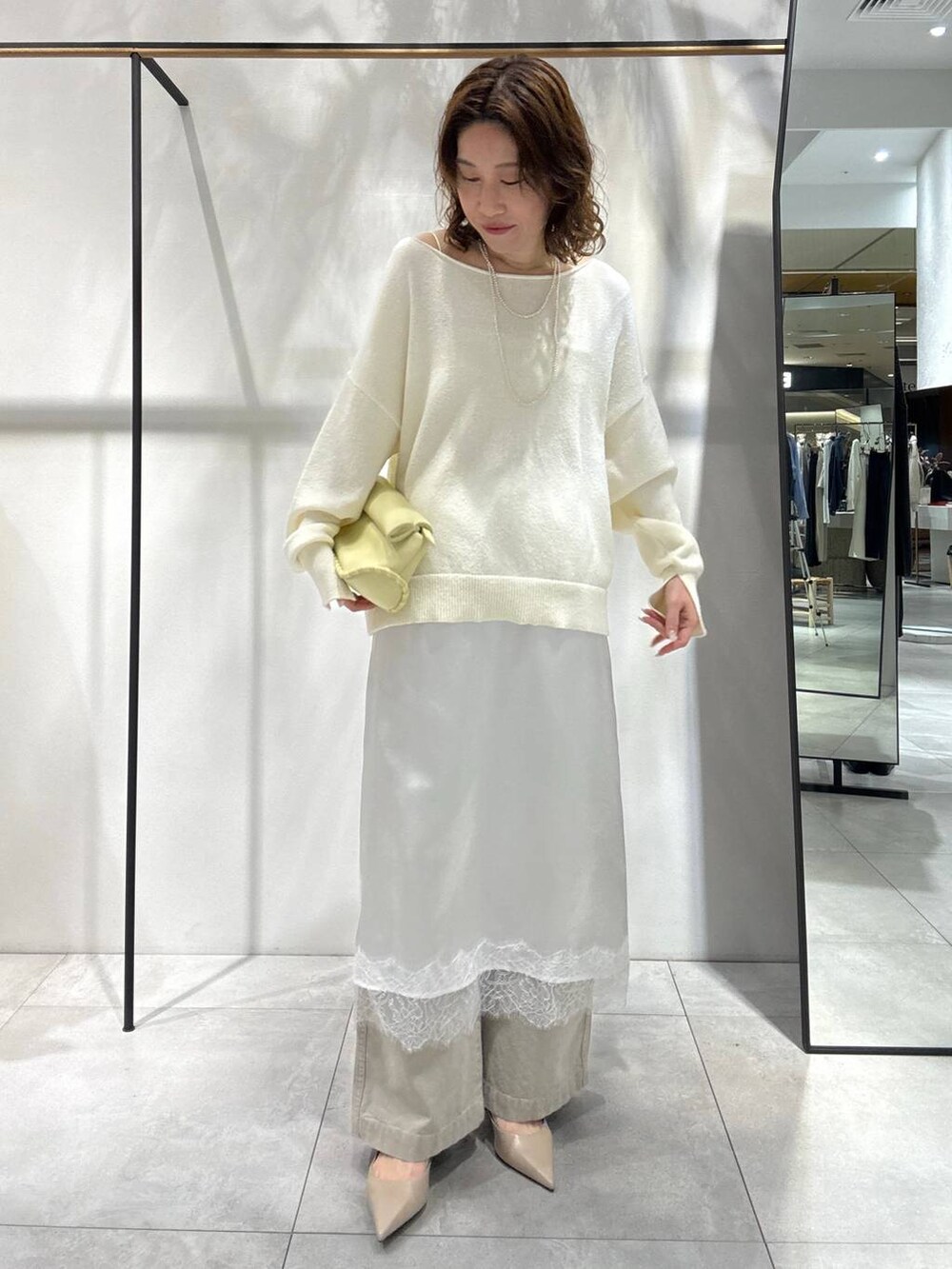 イエロー系のハンドバッグ、ベージュ系のその他パンツ、ベージュ系のトレンチコートを着用したレディースの春コーディネートの3枚目の写真