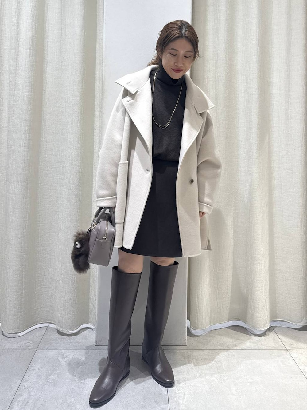 ブラウン系のニット/セーター、ベージュ系のボストンバッグ、ブラウン系のブーツを着用したレディースの冬コーディネートの2枚目の写真