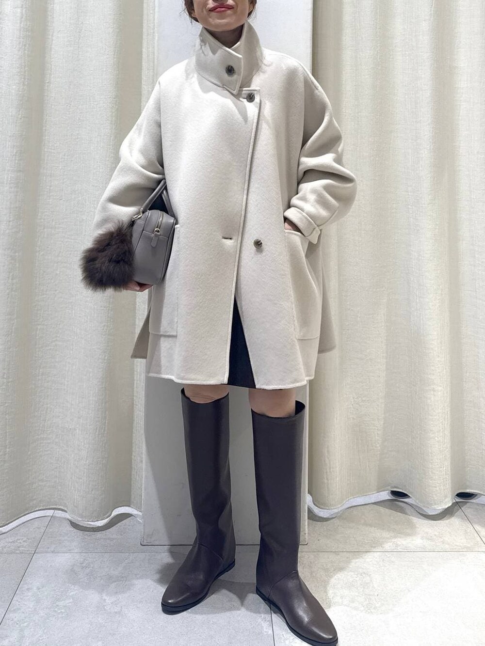 ブラウン系のニット/セーター、ベージュ系のボストンバッグ、ブラウン系のブーツを着用したレディースの冬コーディネートの5枚目の写真