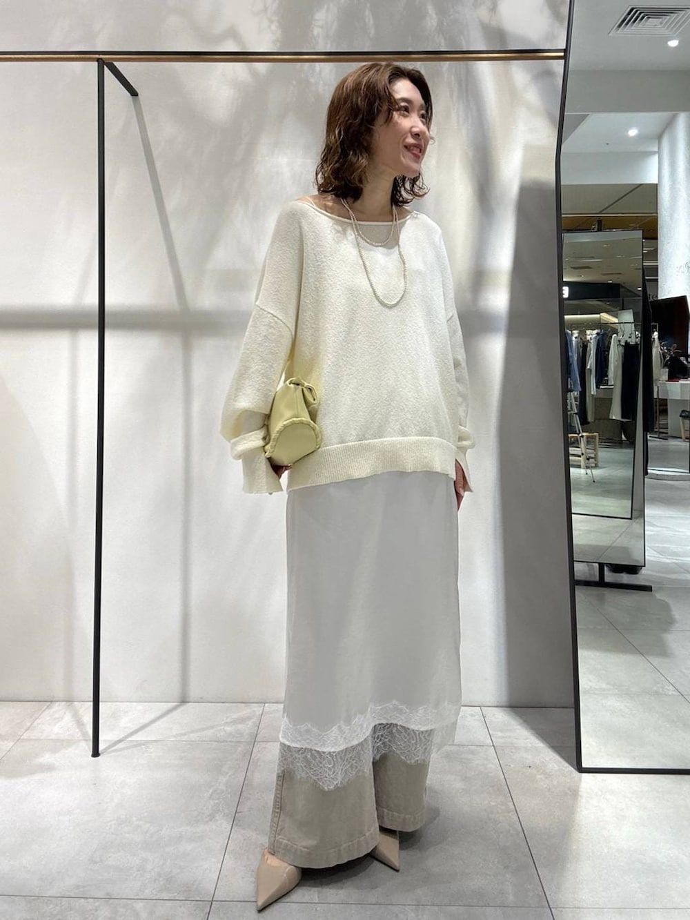 イエロー系のハンドバッグ、ベージュ系のその他パンツ、ベージュ系のトレンチコートを着用したレディースの春コーディネートの2枚目の写真