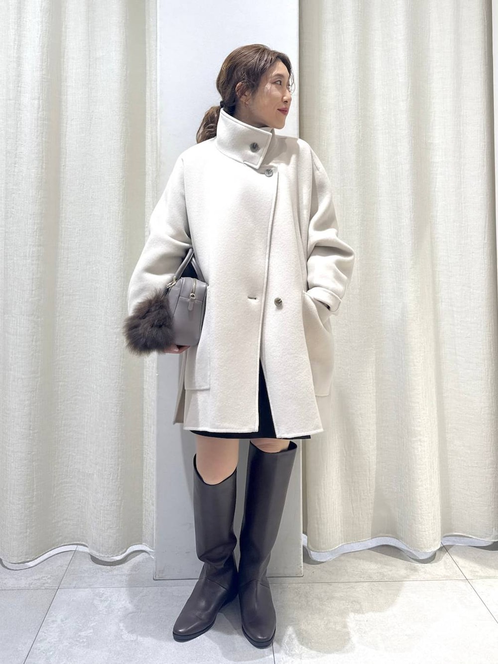 ブラウン系のニット/セーター、ベージュ系のボストンバッグ、ブラウン系のブーツを着用したレディースの冬コーディネートの3枚目の写真