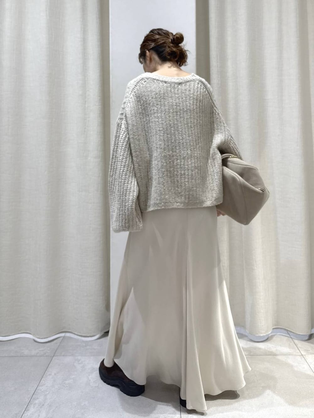 ベージュ系のボストンバッグ、ブラウン系のブーツ、ベージュ系のニット/セーターを着用したレディースの秋コーディネートの5枚目の写真