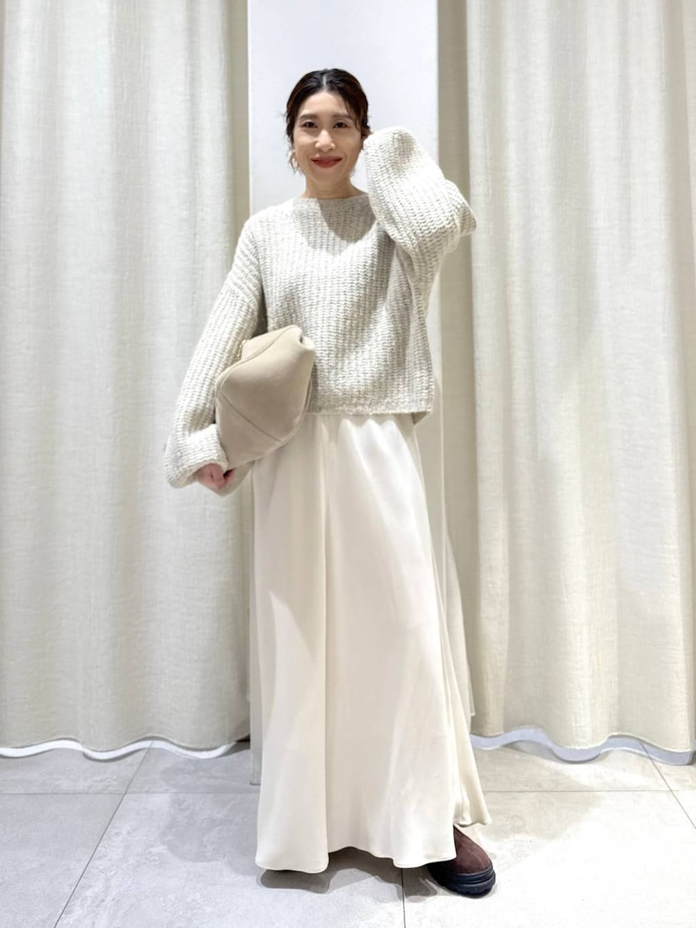 ベージュ系のボストンバッグ、ブラウン系のブーツ、ベージュ系のニット/セーターを着用したレディースの秋コーディネートの3枚目の写真