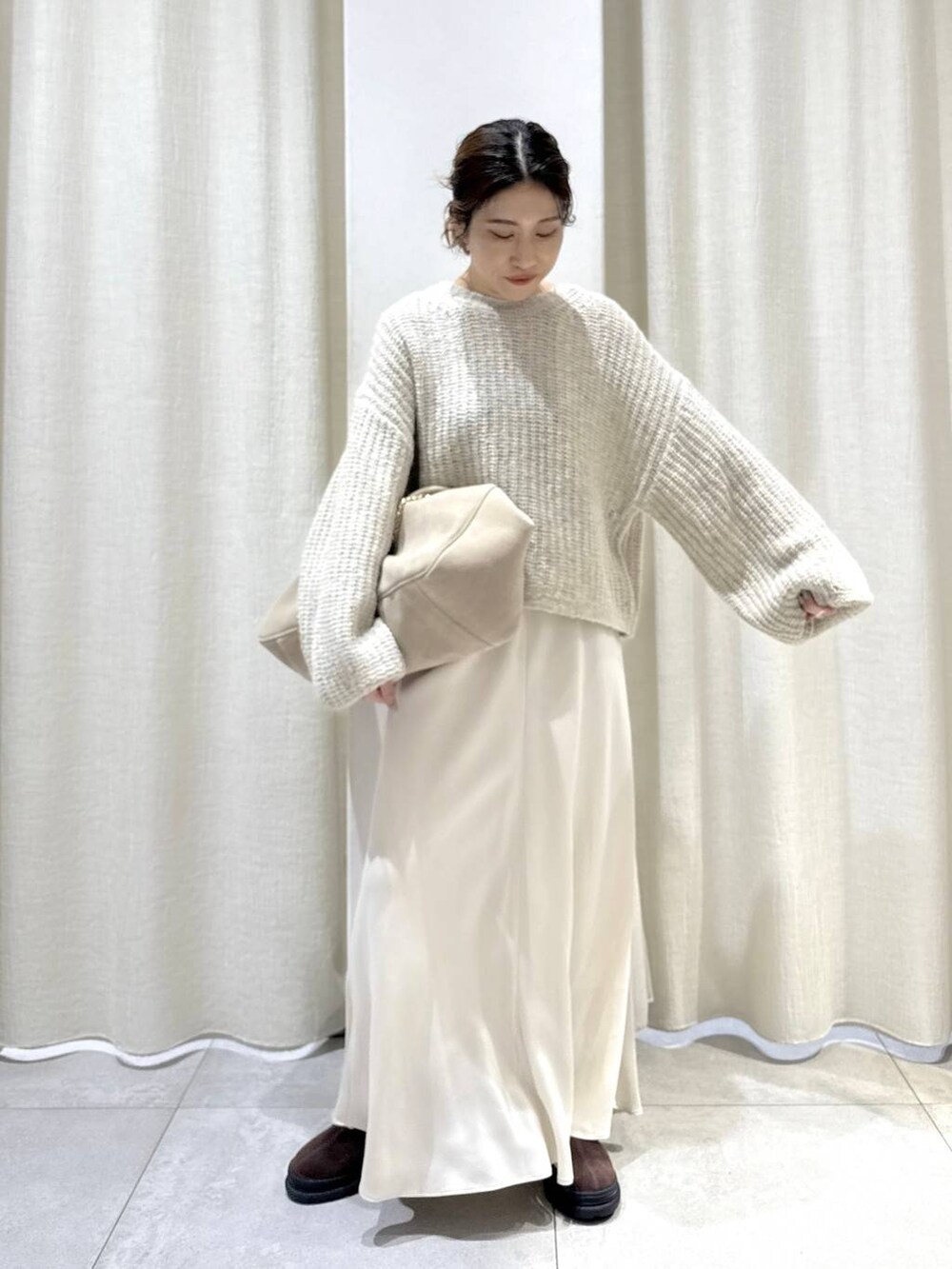 ベージュ系のボストンバッグ、ブラウン系のブーツ、ベージュ系のニット/セーターを着用したレディースの秋コーディネートの4枚目の写真