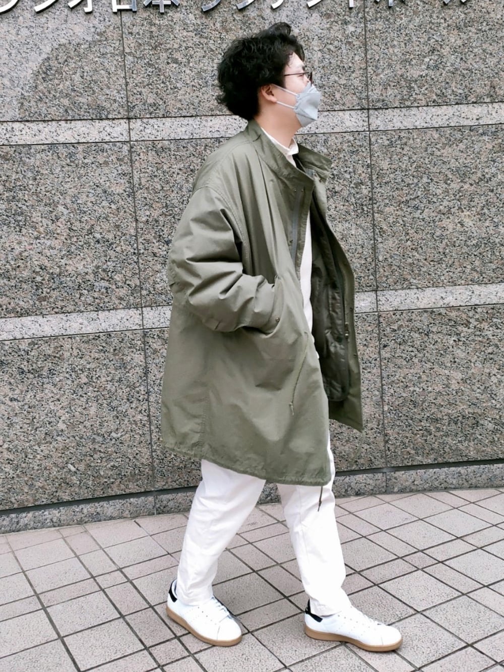 ベージュ系のベスト、ホワイト系のパンツ、ホワイト系のスニーカーを着用したメンズの春コーディネートの2枚目の写真